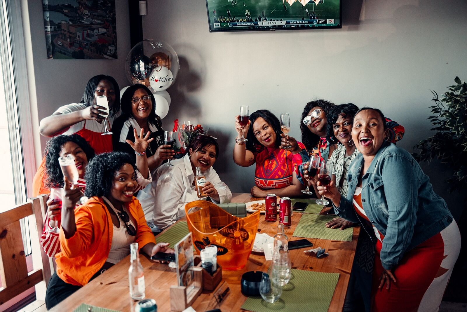 A group celebrating around a table at Captain's Cabin with the rugby on screen