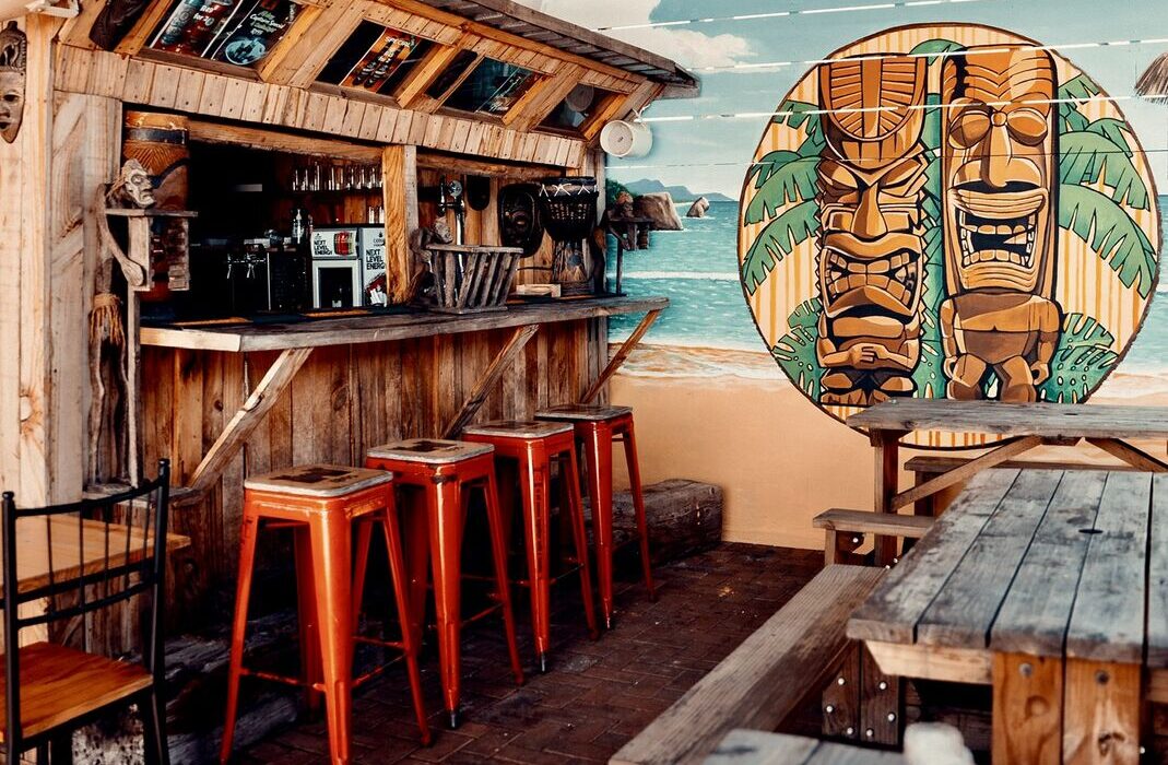 The Tiki-Bar at Captain's Cabin — timber bar, orange stools and painted tiki mural